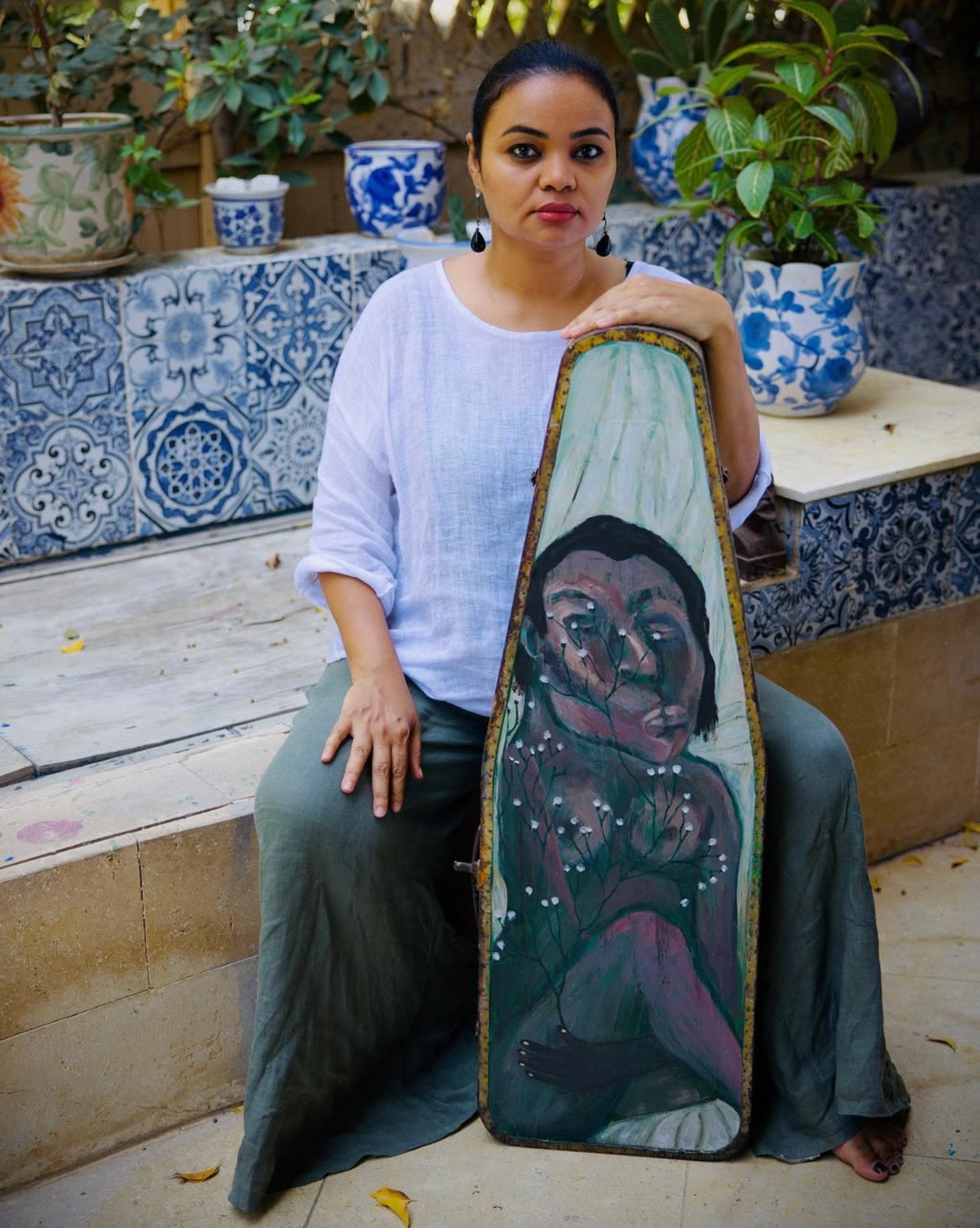 A photograph of Egyptian artist Souad Abdelrassoul painting an artwork in her studio